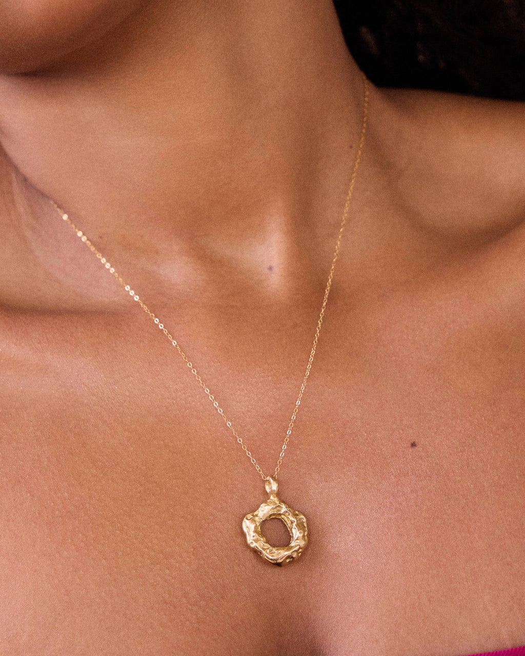Gold necklace with a circular pendant on a person's neck