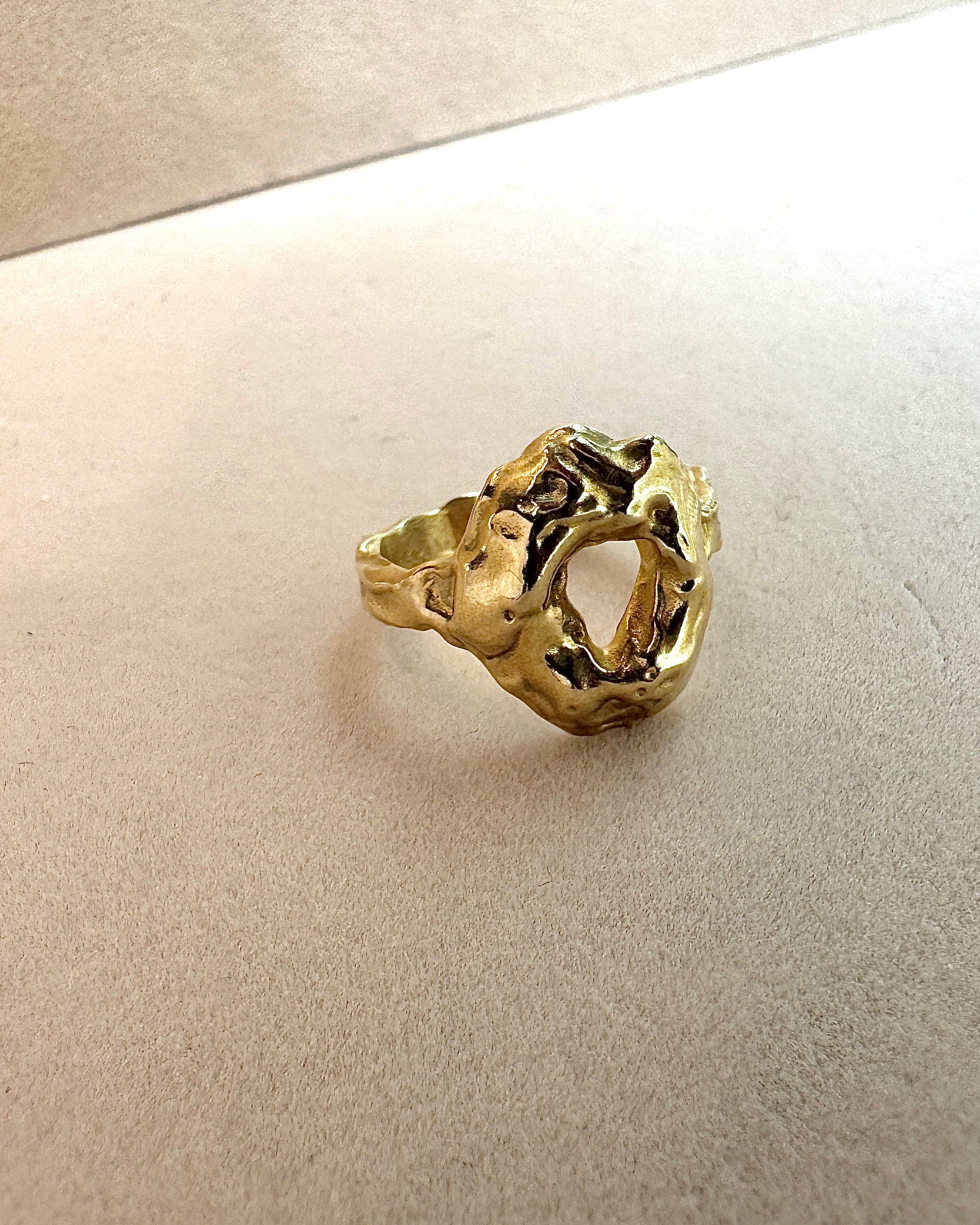 Gold ring with a textured design on a beige background