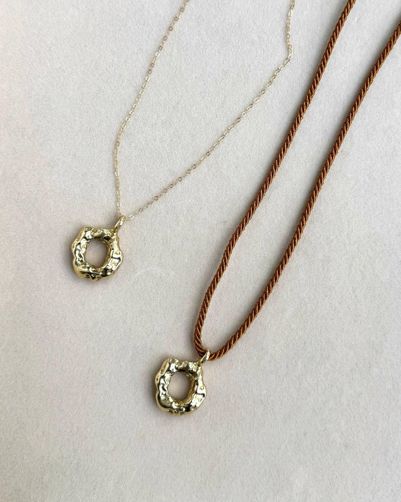 Two necklaces with circular pendants on a white background