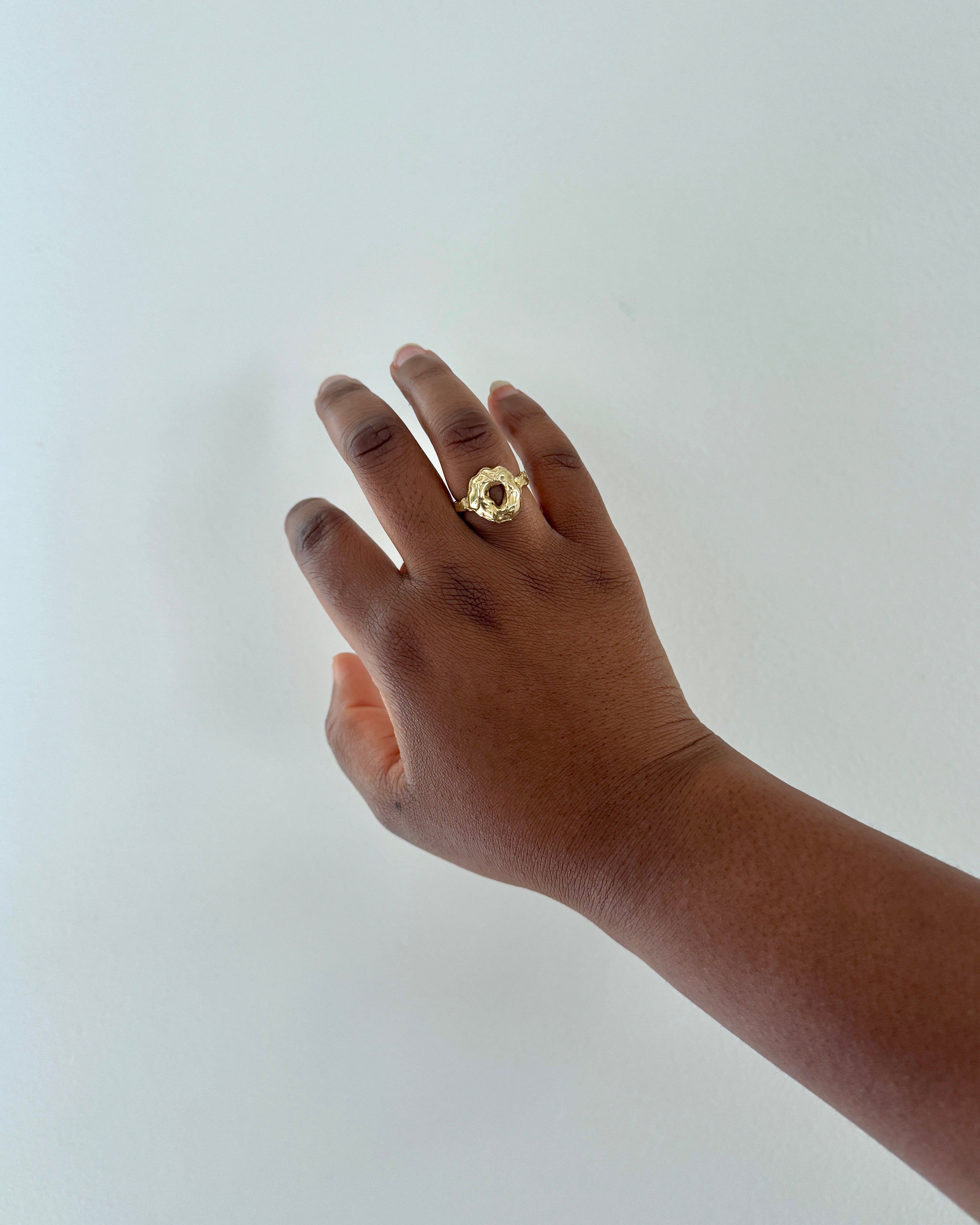 Hand wearing a gold ring on a white background