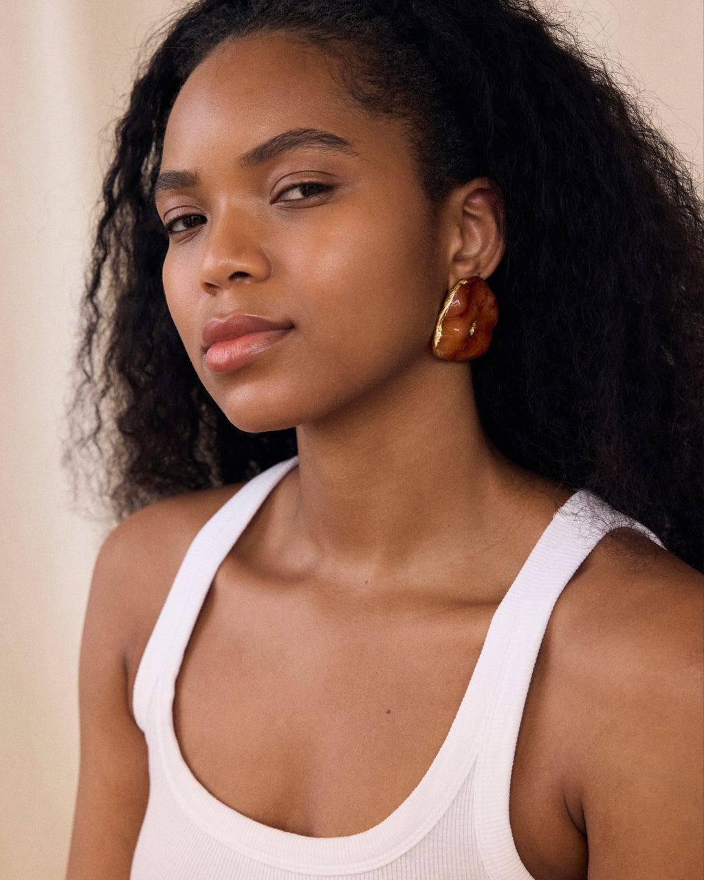 Woman wearing a white tank top with a neutral background