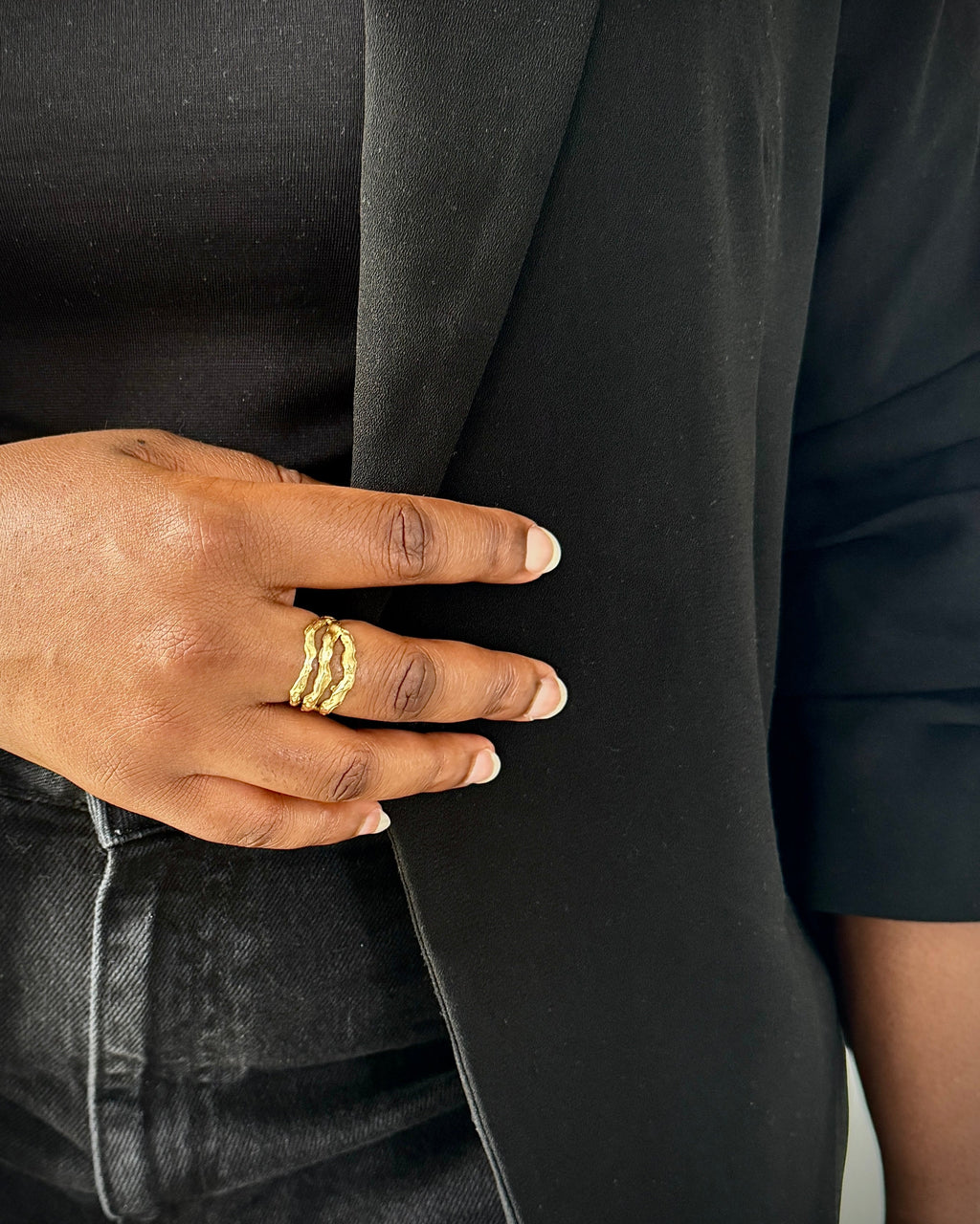 Close-up of a hand wearing gold rings on a black background