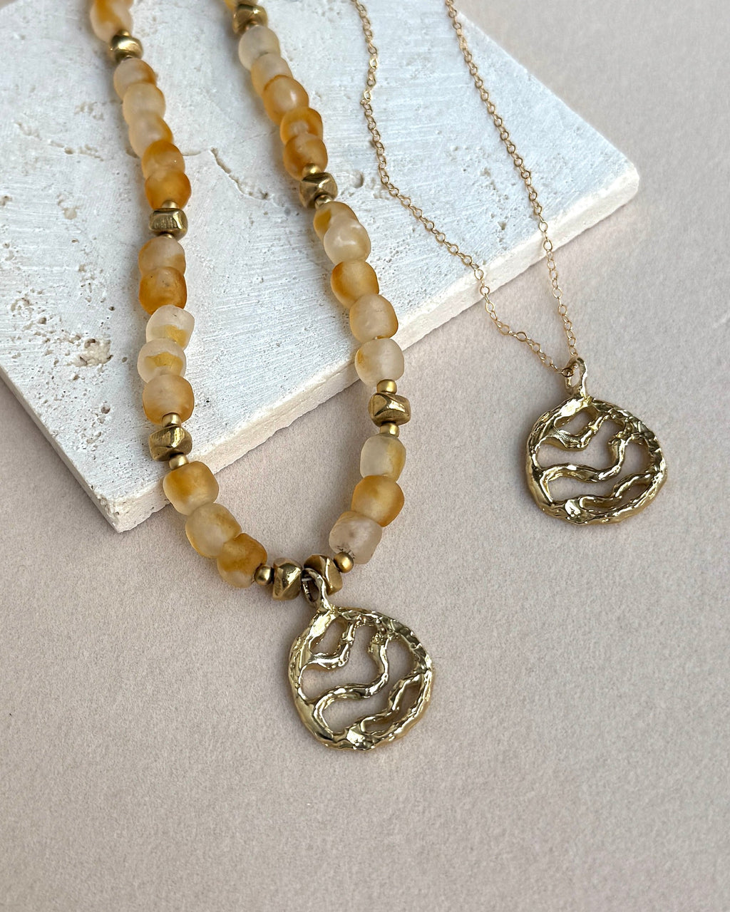 Necklace with beaded chain and gold pendant on a light background