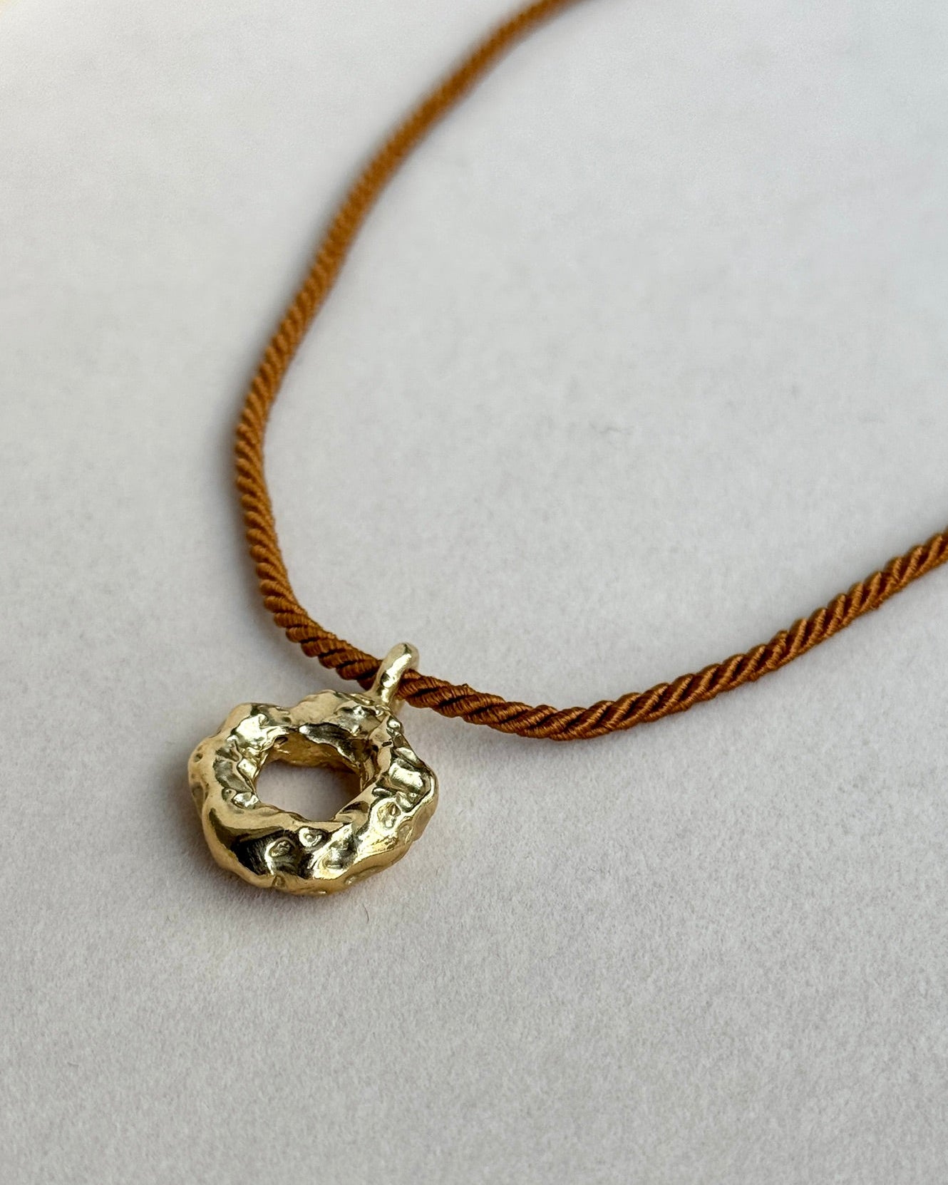 Gold necklace with a circular pendant on a white background