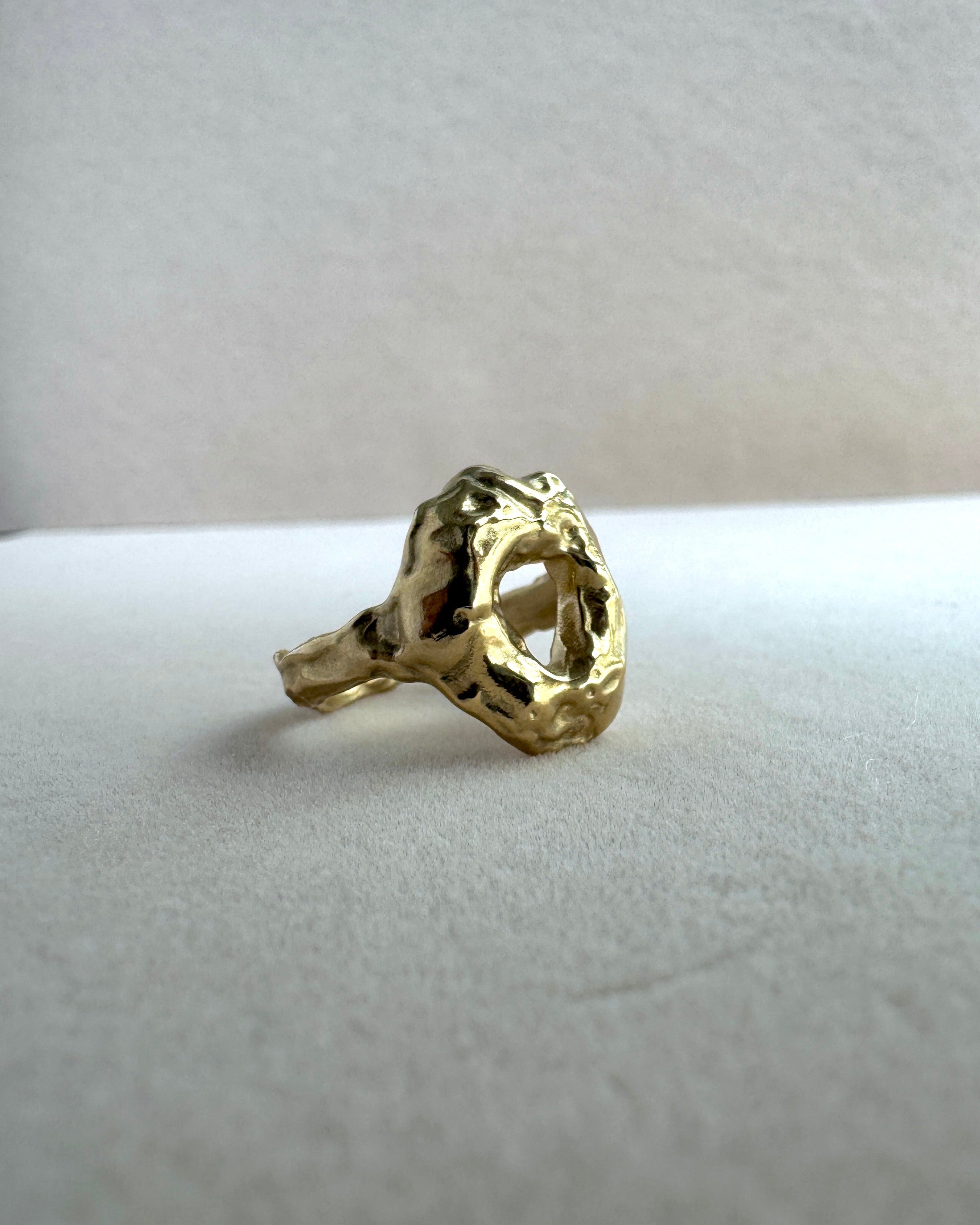Gold ring with a textured design on a white cushion