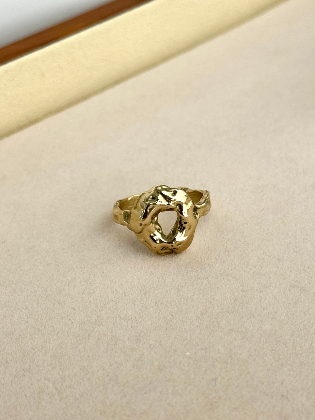 Gold ring on a beige cushion