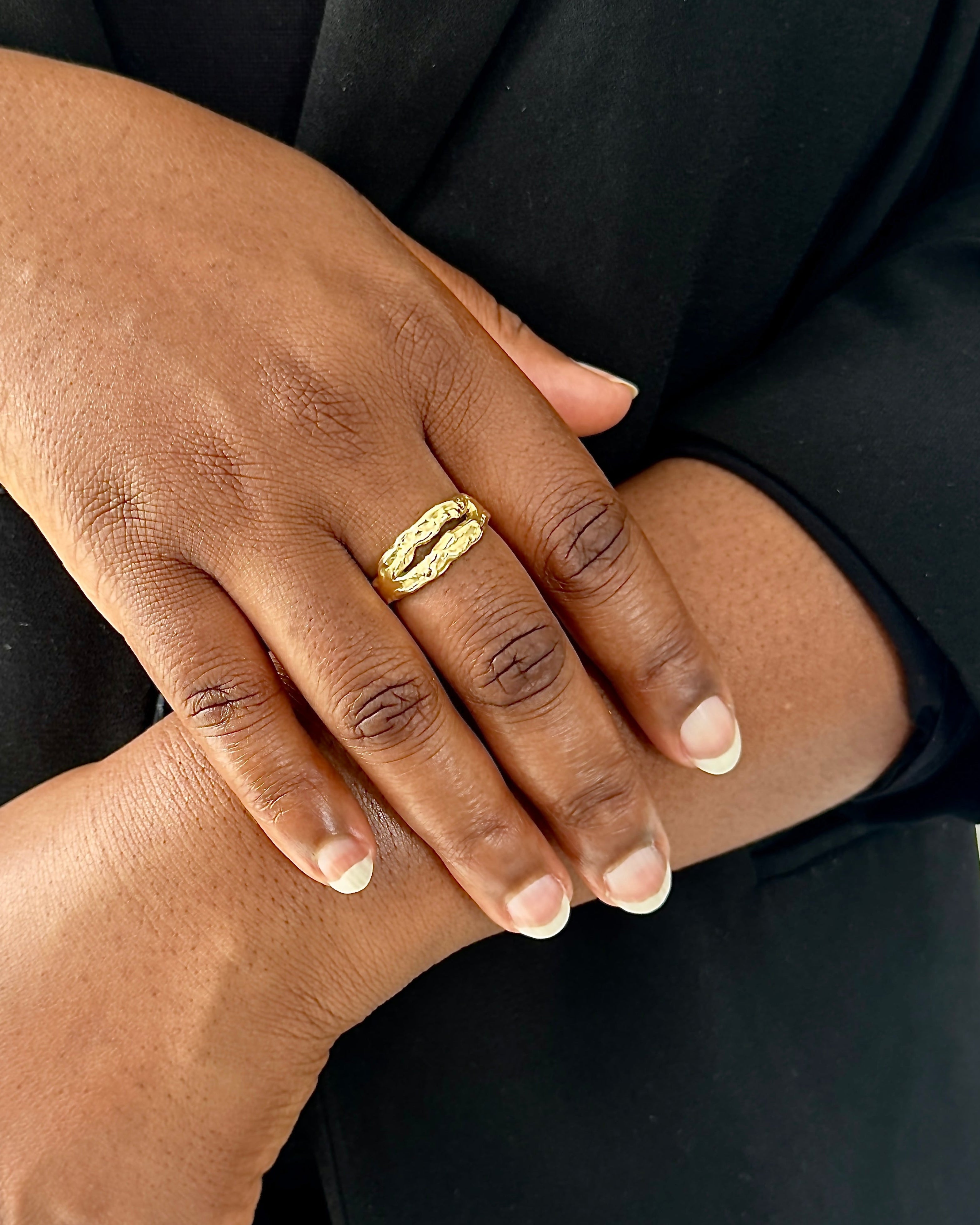 Person wearing a gold ring on a plain background