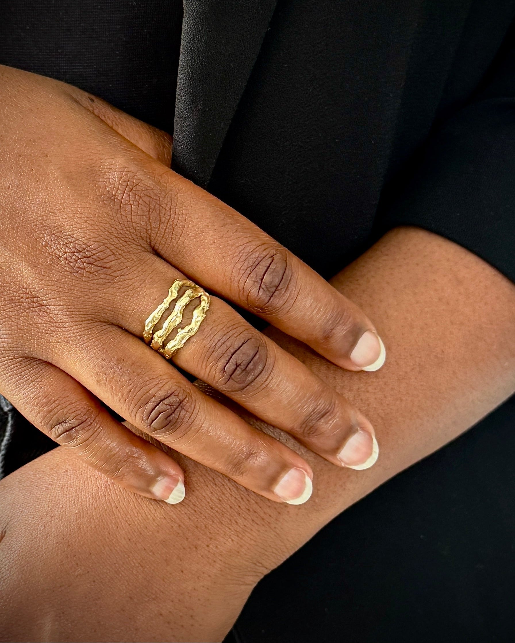 Hand wearing a gold ring with a black background