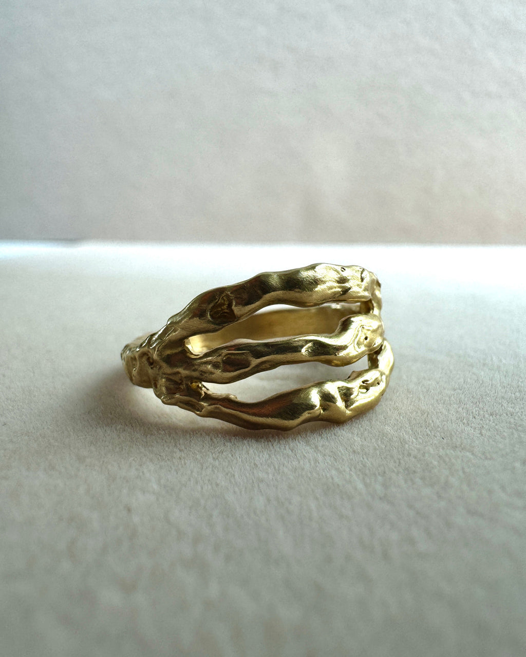 Gold ring with a textured design on a light gray background