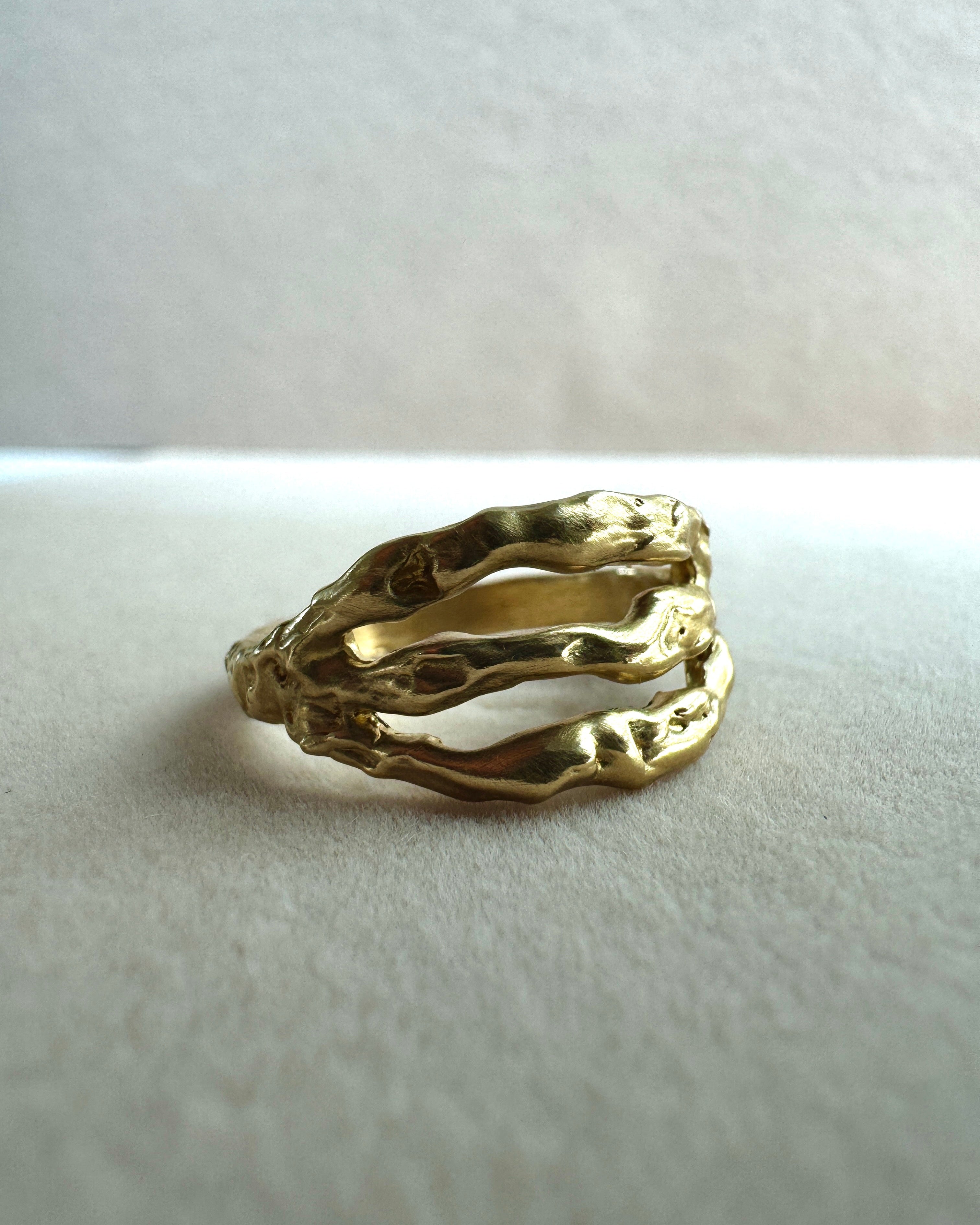 Gold ring with a textured design on a light gray background