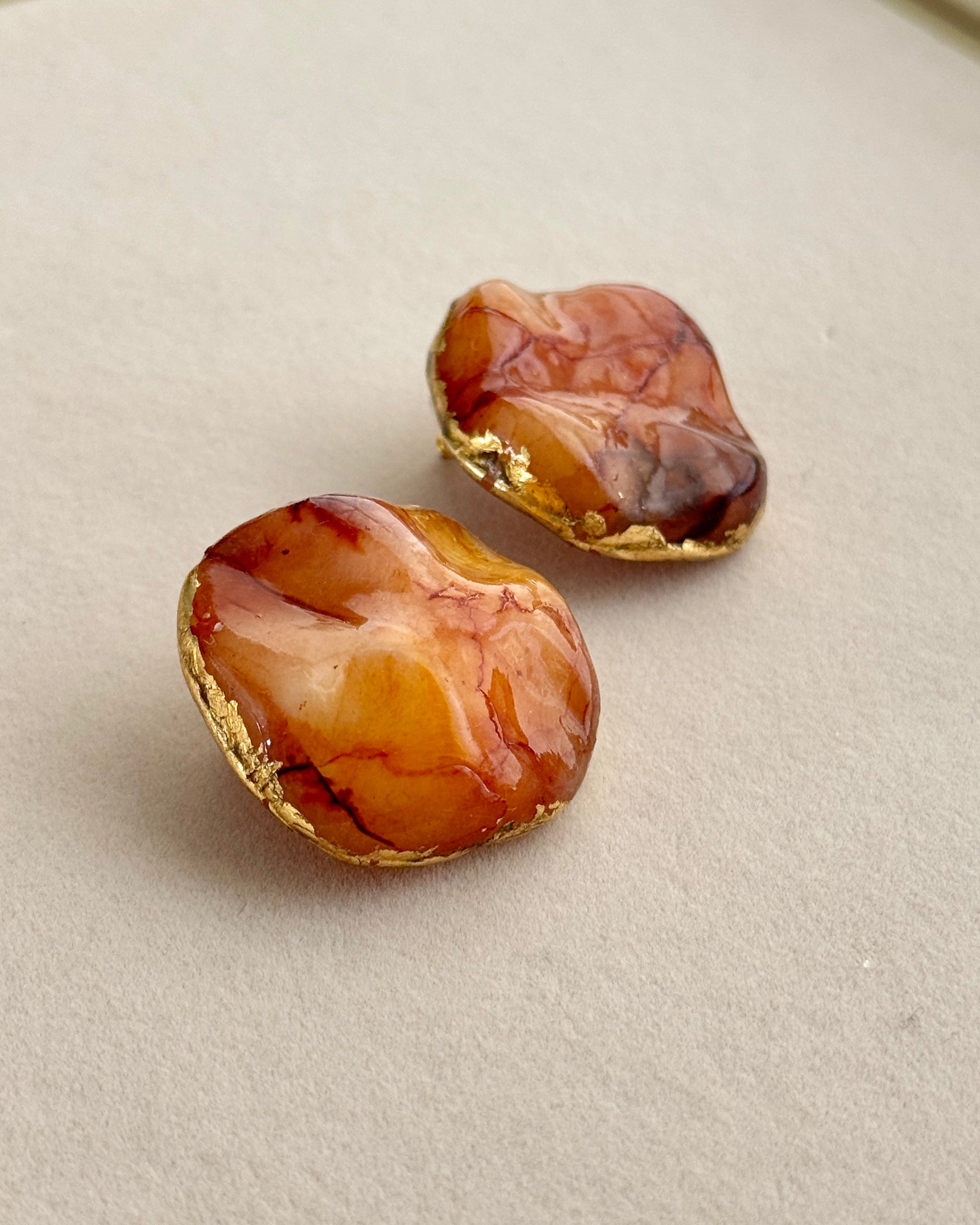 Two amber stone earrings on a beige surface